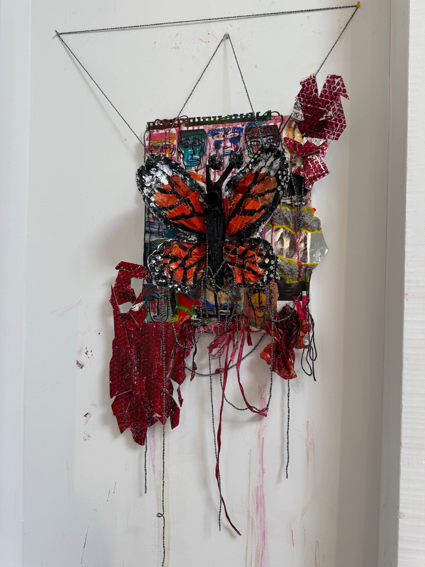 Trapped installed on a wall, suspended by cords with layered elements trailing below